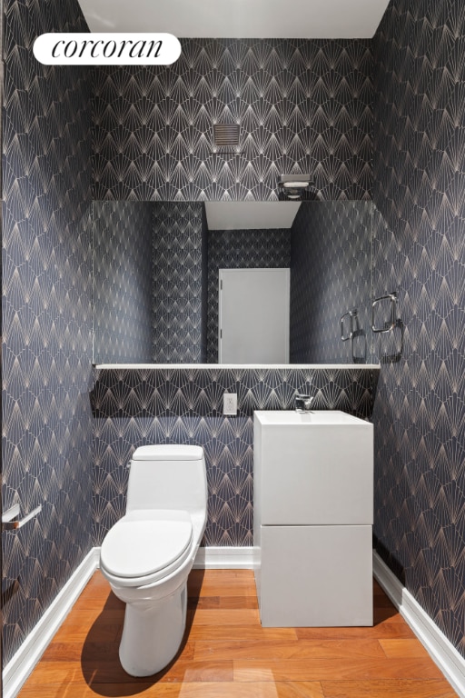 bathroom featuring vanity, wood-type flooring, and toilet