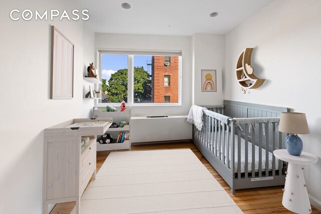 bedroom with light hardwood / wood-style flooring and a crib