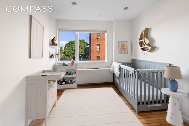 bedroom featuring a nursery area and wood finished floors