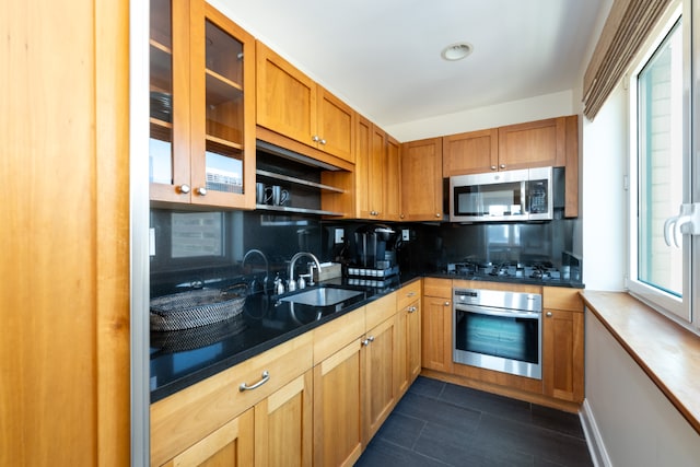 kitchen with dark tile patterned floors, appliances with stainless steel finishes, sink, and decorative backsplash