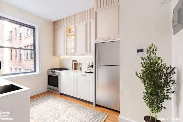 kitchen featuring appliances with stainless steel finishes, light hardwood / wood-style floors, white cabinets, and electric panel