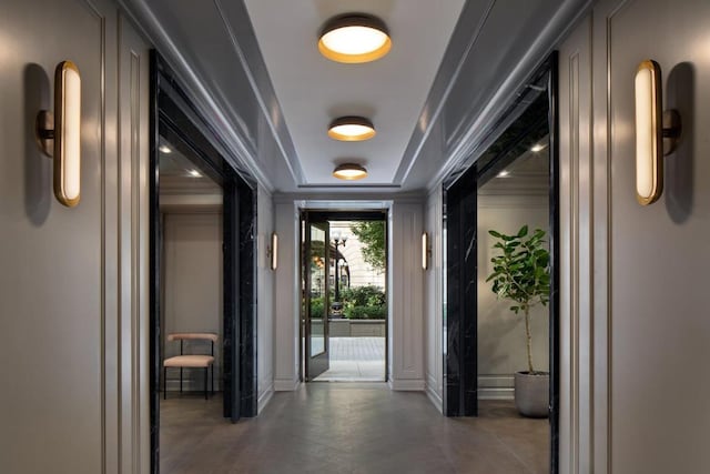 hallway with a raised ceiling and crown molding