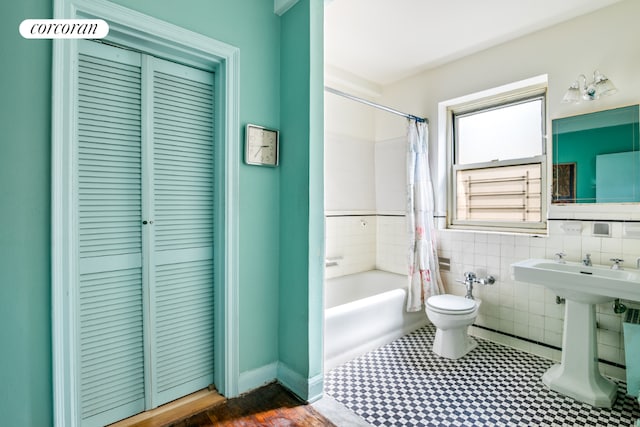 full bathroom with toilet, shower / bathtub combination with curtain, tile walls, and sink