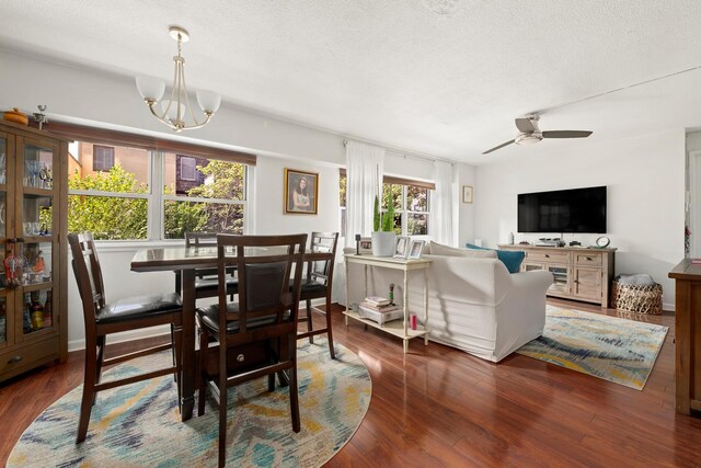 dining space with dark wood-type flooring, plenty of natural light, and ceiling fan with notable chandelier