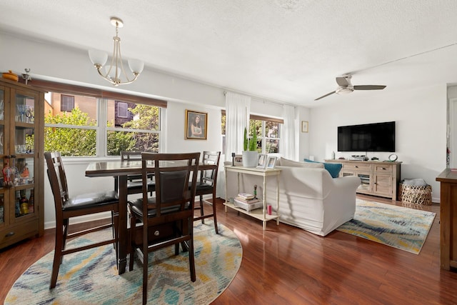 dining area with ceiling fan with notable chandelier, a textured ceiling, and wood finished floors