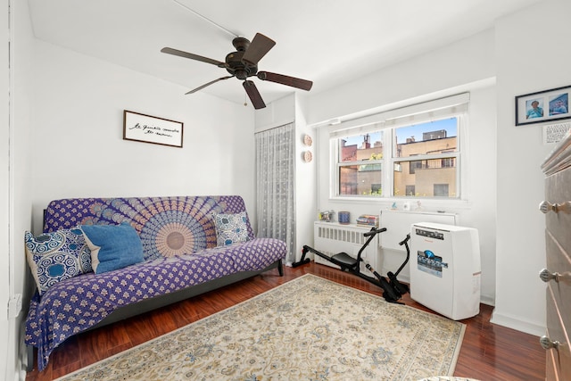 living room with radiator, a ceiling fan, baseboards, and wood finished floors