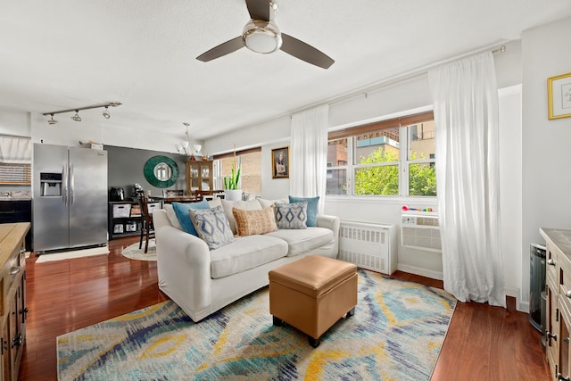 living area with ceiling fan with notable chandelier, radiator heating unit, wood finished floors, and rail lighting