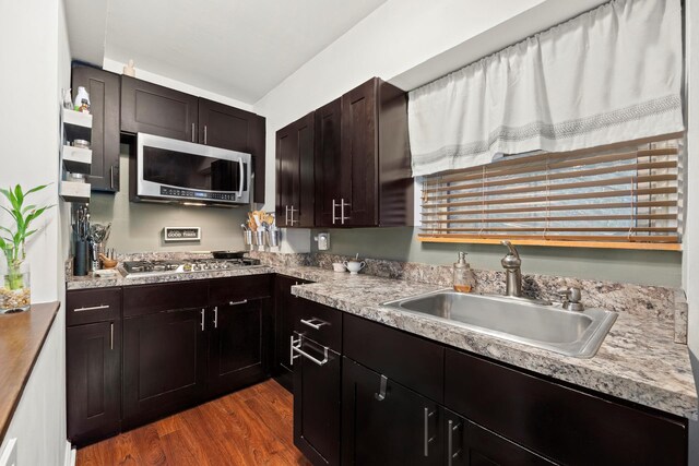 kitchen with appliances with stainless steel finishes, plenty of natural light, dark hardwood / wood-style flooring, dark brown cabinets, and sink