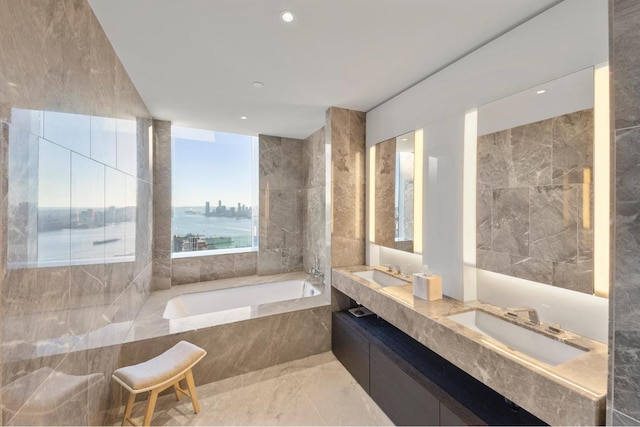 bathroom with vanity, tiled tub, tile walls, and a water view