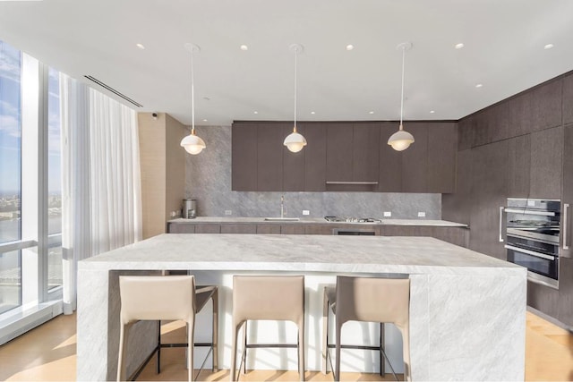 kitchen with sink, a breakfast bar, hanging light fixtures, stainless steel appliances, and tasteful backsplash