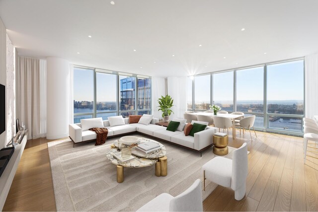 living room featuring a water view, plenty of natural light, a wall of windows, and light hardwood / wood-style floors