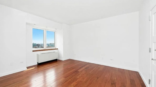 unfurnished room with radiator and wood-type flooring