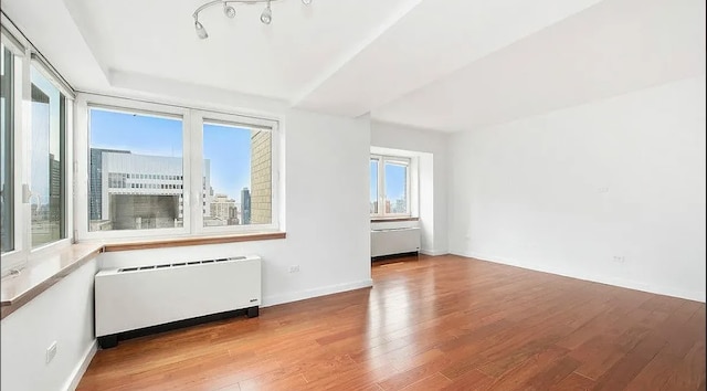 unfurnished room with radiator and light wood-type flooring