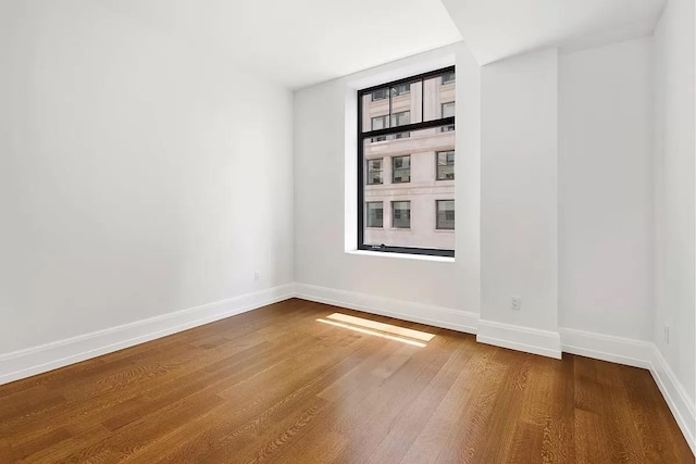 spare room featuring baseboards and dark wood finished floors