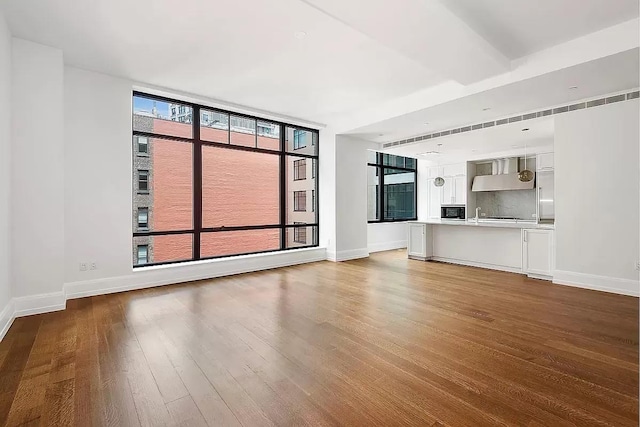 unfurnished living room featuring baseboards, floor to ceiling windows, and wood finished floors