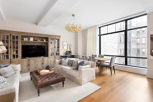 living room featuring plenty of natural light, light wood-style flooring, and an inviting chandelier