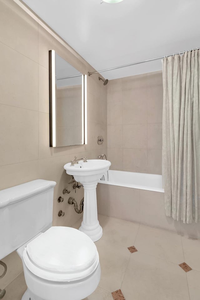 bathroom with tiled shower / bath, toilet, tile patterned flooring, and tile walls