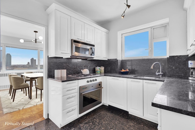 kitchen with stainless steel appliances, tasteful backsplash, a sink, and white cabinetry