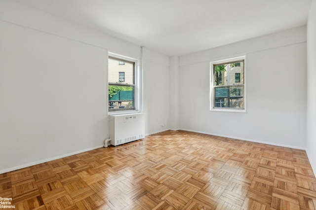 empty room featuring baseboards, radiator heating unit, and plenty of natural light
