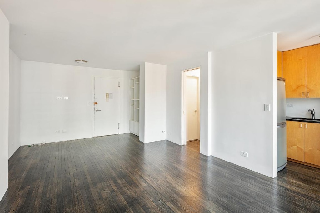 unfurnished living room with dark hardwood / wood-style floors and sink