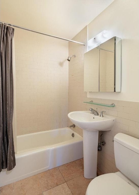 bathroom featuring tile walls, tile patterned floors, toilet, and shower / tub combo with curtain