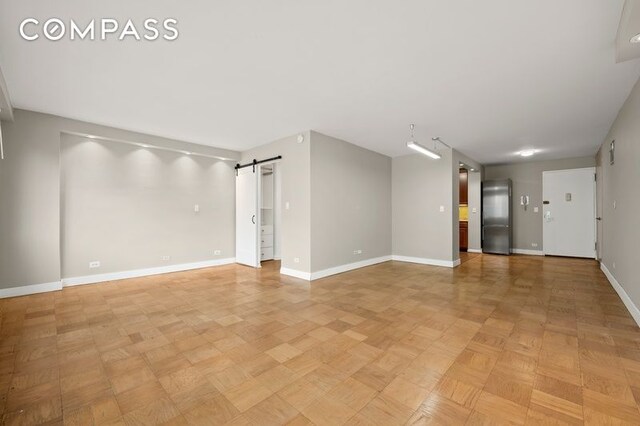 spare room with baseboards and a barn door