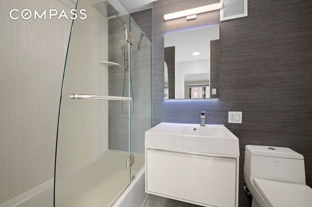 bathroom with enclosed tub / shower combo, visible vents, toilet, and vanity