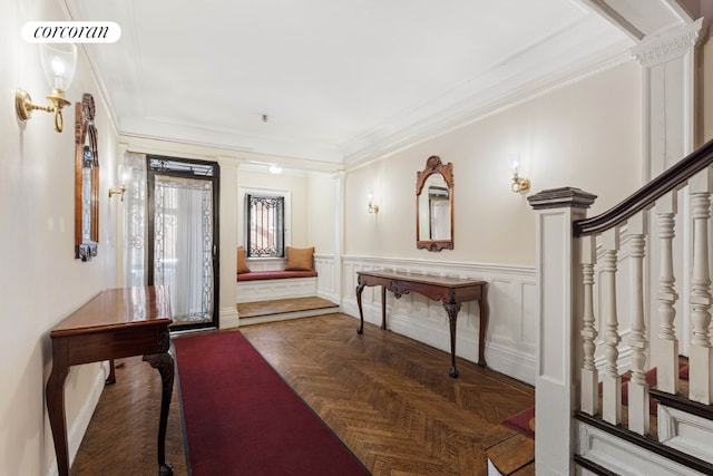 foyer entrance featuring dark parquet flooring, ornamental molding, and ornate columns