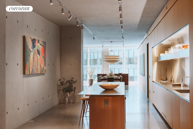 100 E 53rd St Unit 8C, New York City, NY 10022 - kitchen featuring track lighting, open shelves, a kitchen island, a kitchen breakfast bar, and light countertops