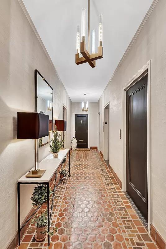 corridor with a chandelier, ornamental molding, and baseboards