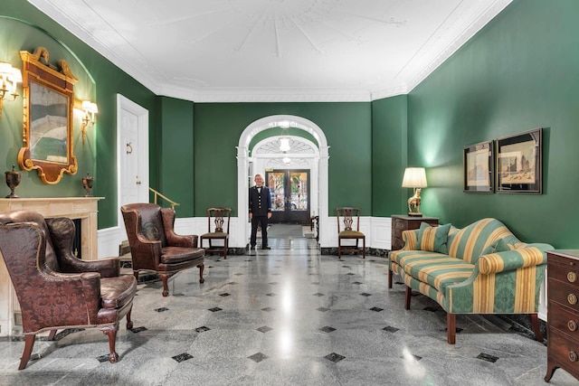 living area featuring ornamental molding, a wainscoted wall, and a decorative wall