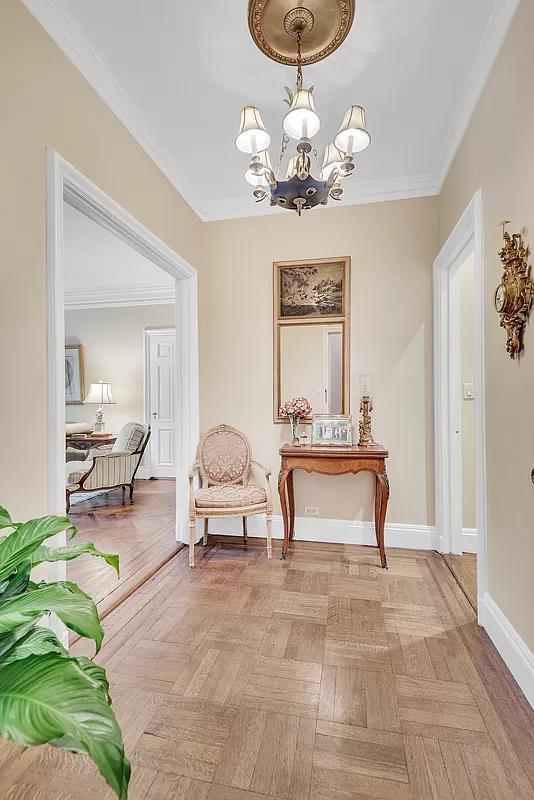 hall featuring ornamental molding, a chandelier, and baseboards