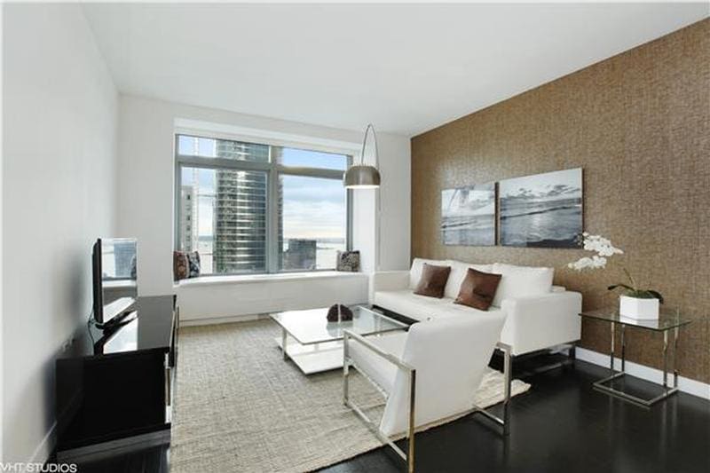 living room featuring baseboards, an accent wall, and wallpapered walls