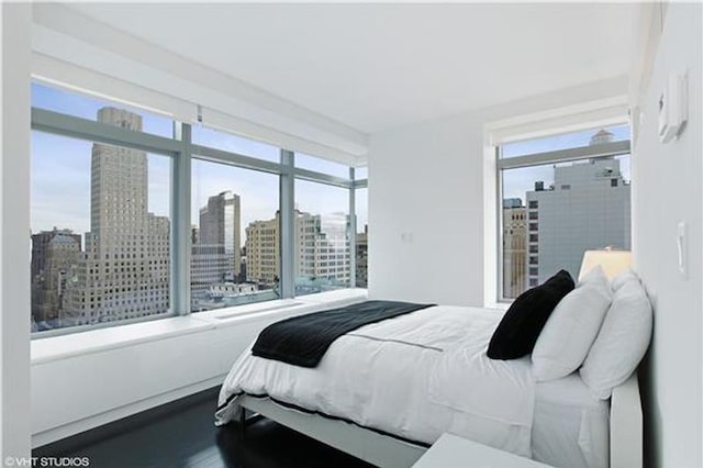 bedroom with a view of city and multiple windows