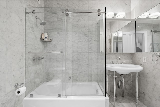 bathroom featuring sink, combined bath / shower with glass door, decorative backsplash, and tile walls