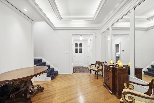 entrance foyer featuring a tray ceiling, crown molding, light wood-style flooring, stairway, and baseboards