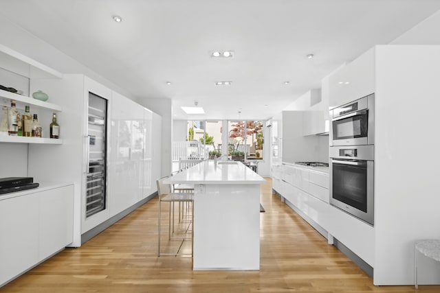 kitchen featuring appliances with stainless steel finishes, a breakfast bar, a center island with sink, and white cabinets