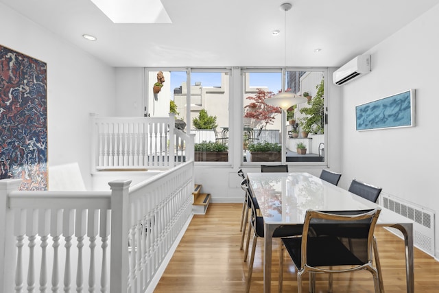 dining room featuring light wood-type flooring, a wall unit AC, and a skylight