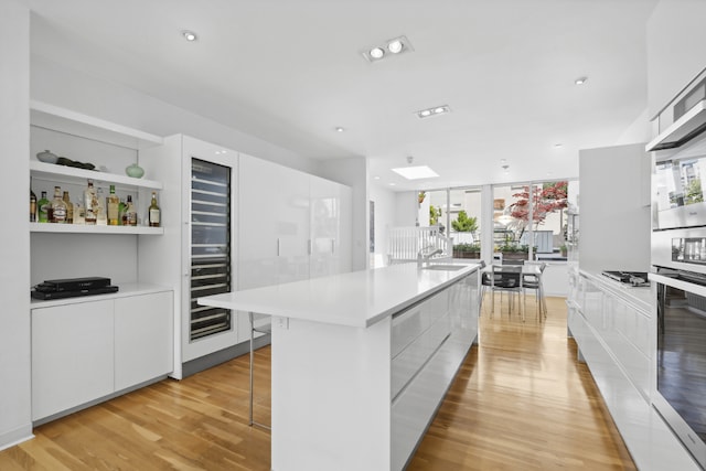 kitchen featuring appliances with stainless steel finishes, white cabinets, a kitchen breakfast bar, a center island, and light hardwood / wood-style flooring