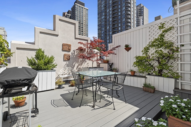 wooden terrace featuring outdoor dining space, a city view, and a grill