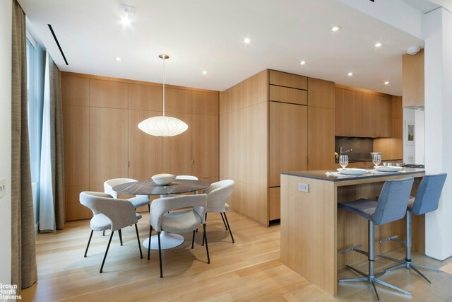 kitchen featuring a breakfast bar area, pendant lighting, light wood-type flooring, and kitchen peninsula