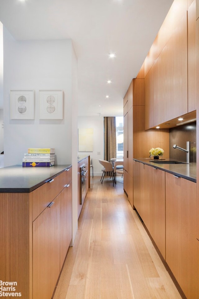 kitchen featuring sink, light wood-type flooring, and decorative backsplash