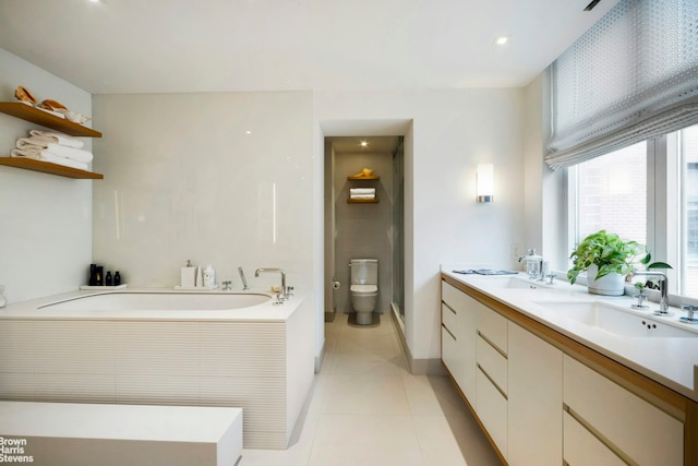 bathroom with tile patterned floors, toilet, vanity, and a washtub