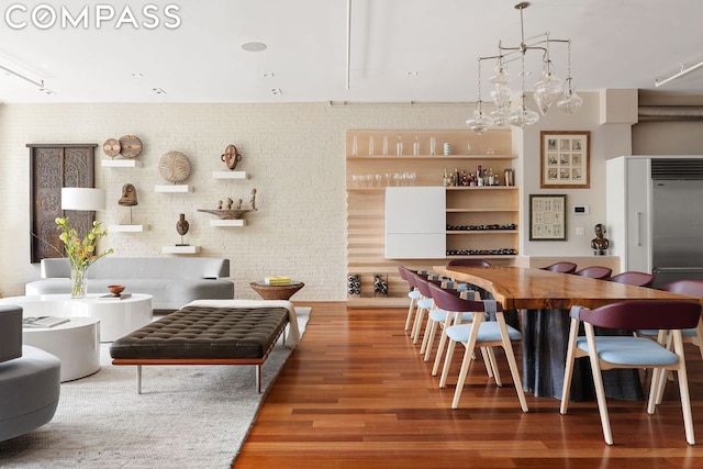 dining space featuring wood-type flooring and brick wall