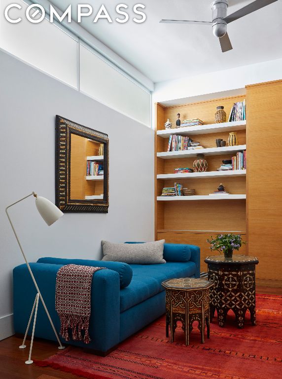 living area with ceiling fan and built in shelves