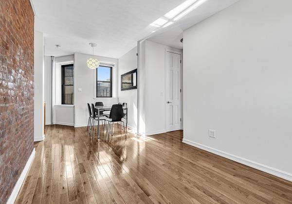 interior space with hardwood / wood-style floors and brick wall