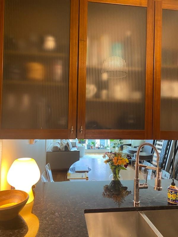 interior details with stone counters, glass insert cabinets, and a sink