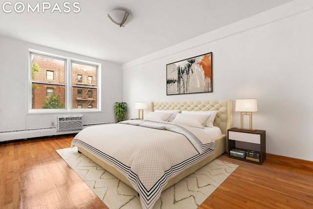 bedroom with a wall unit AC and light hardwood / wood-style floors