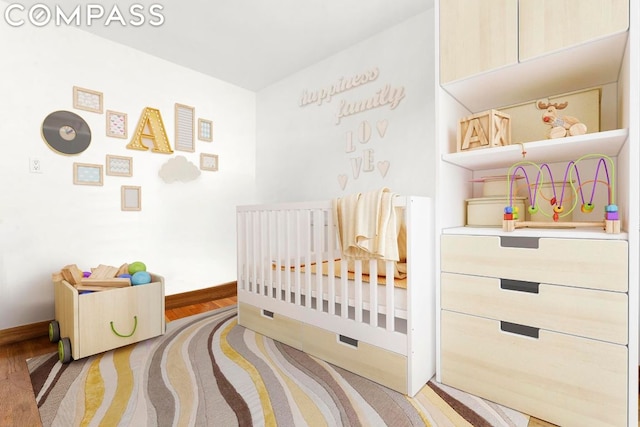 bedroom featuring hardwood / wood-style flooring and a crib