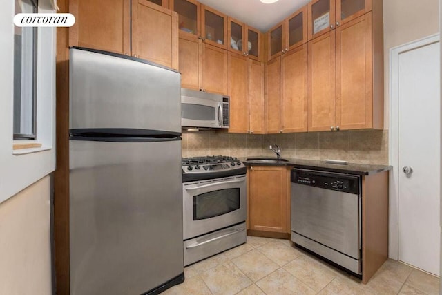 kitchen with stainless steel appliances, tasteful backsplash, sink, and light tile patterned flooring